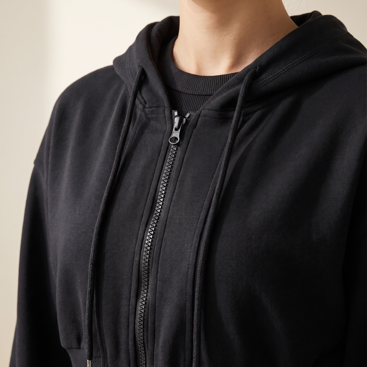 Dettaglio del cappuccio con coulisse e della zip della felpa nera