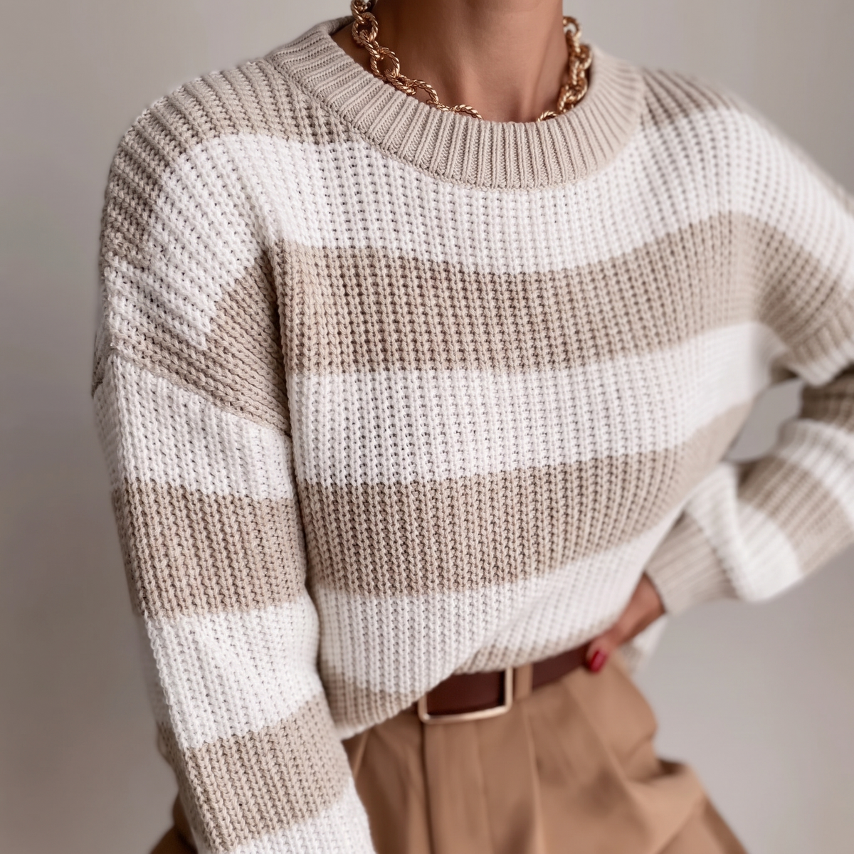 Dettaglio della maglia grossa a righe khaki e bianco e dello scollo rotondo