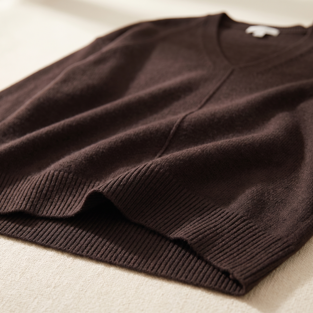 Dettaglio dello scollo a V e del bordo a coste del maglione donna