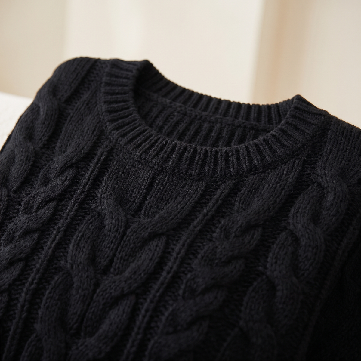Dettaglio del motivo a trecce e del girocollo a coste del maglione nero